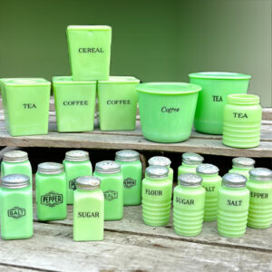 A collection of McKee and Jeannette Jadite canisters and shakers.