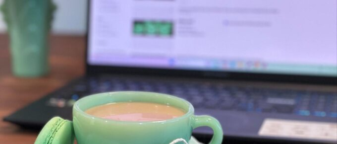 Fire-king Restaurant Ware Jadeite cup and saucer with macarons and "What's it Worth?" tag, styled in front of a laptop displaying Jadeite eBay listings