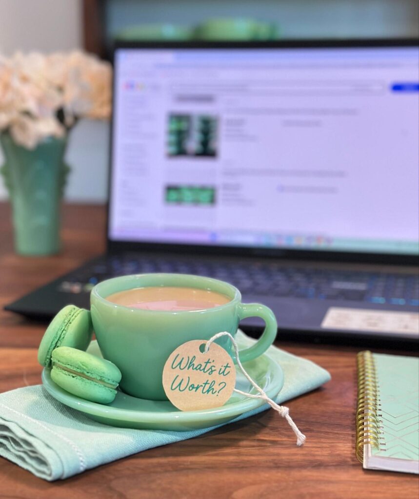 Fire-king Restaurant Ware Jadeite cup and saucer with macarons and "What's it Worth?" tag, styled in front of a laptop displaying Jadeite eBay listings